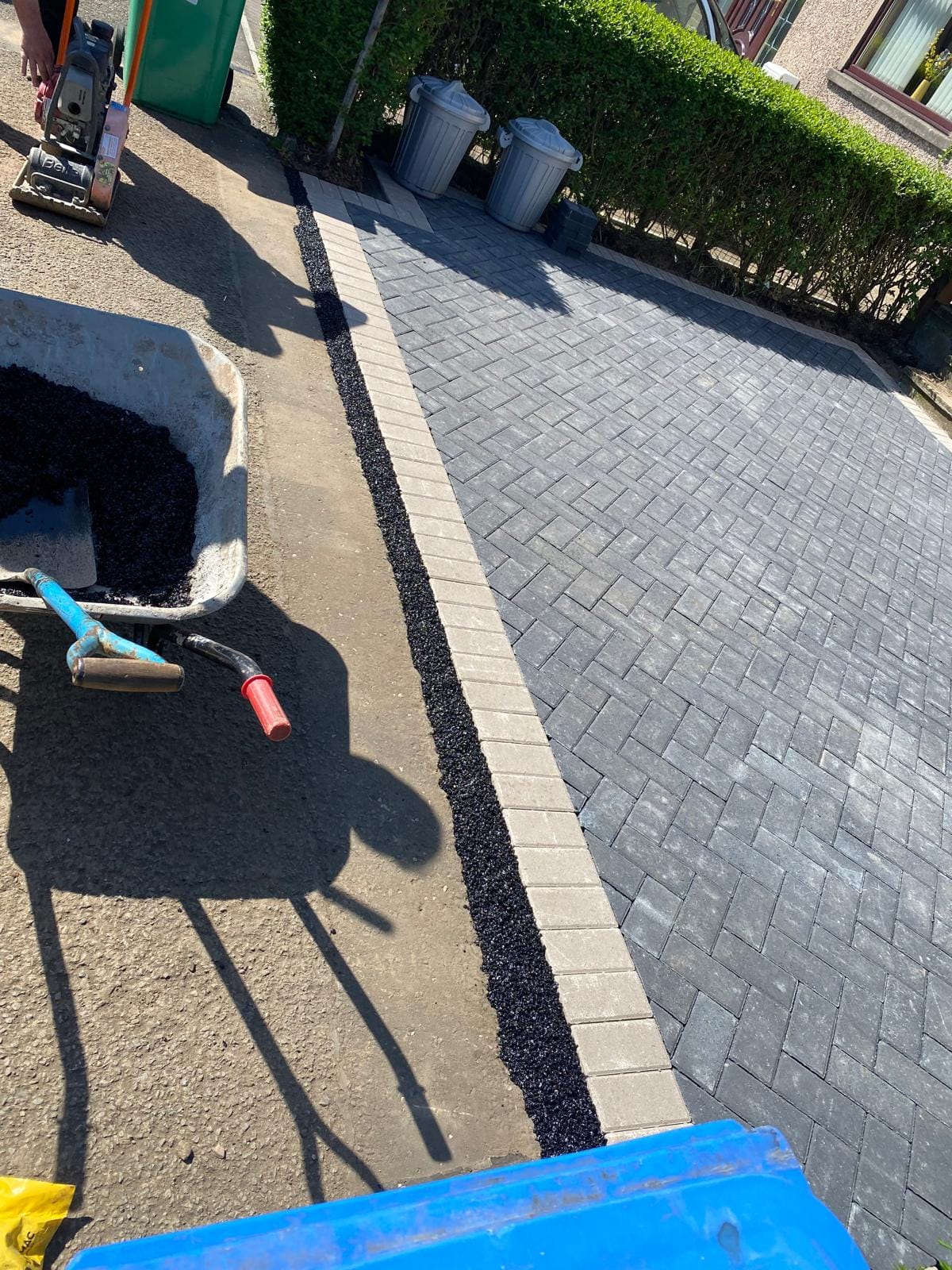 Grey herringbone block paving with edging being laid